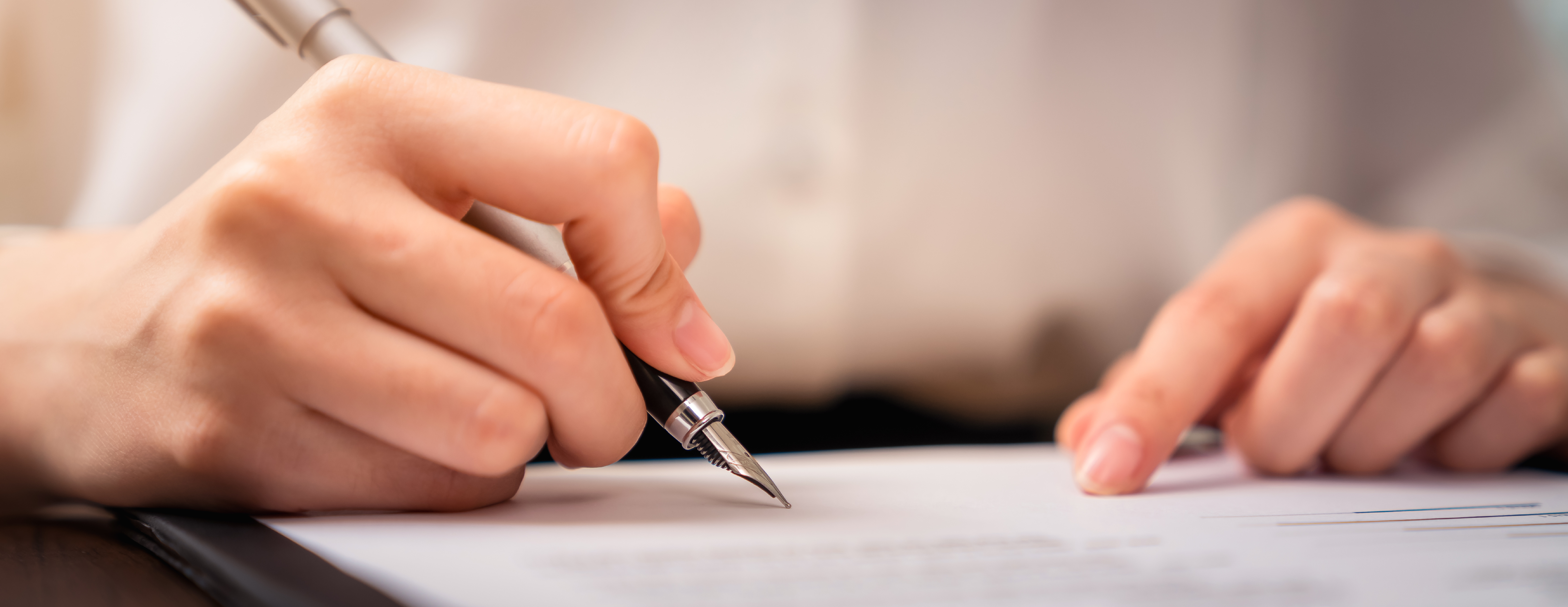 Person filling out a form with a pen.